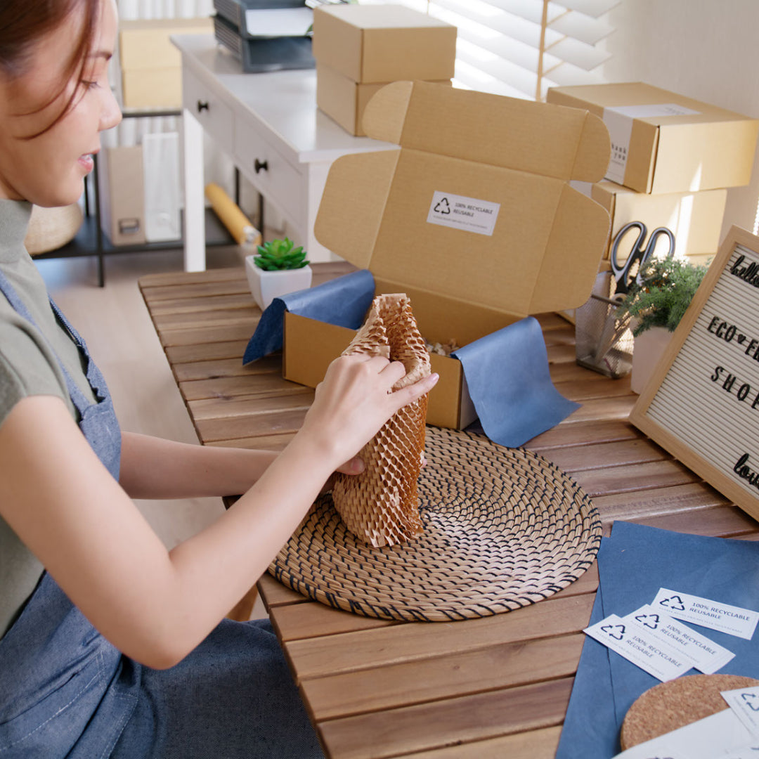 Person packing orders in sustainable paper packaging, showcasing the importance of eco-friendly packaging practices in business.